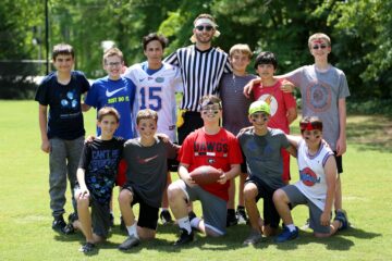Staff pose with campers on an athletics field