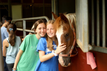 Campers pet a horse at the barn
