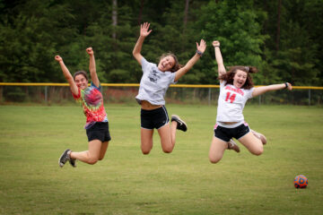 Campers jump into the air on an athletic field