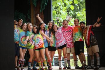 Camp staff in tie-dye posing onstage